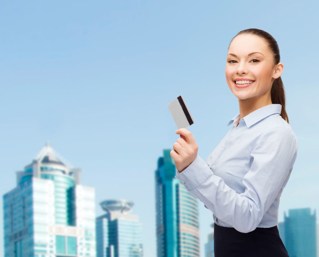 Business woman holding a credit card with a cityscape behind her