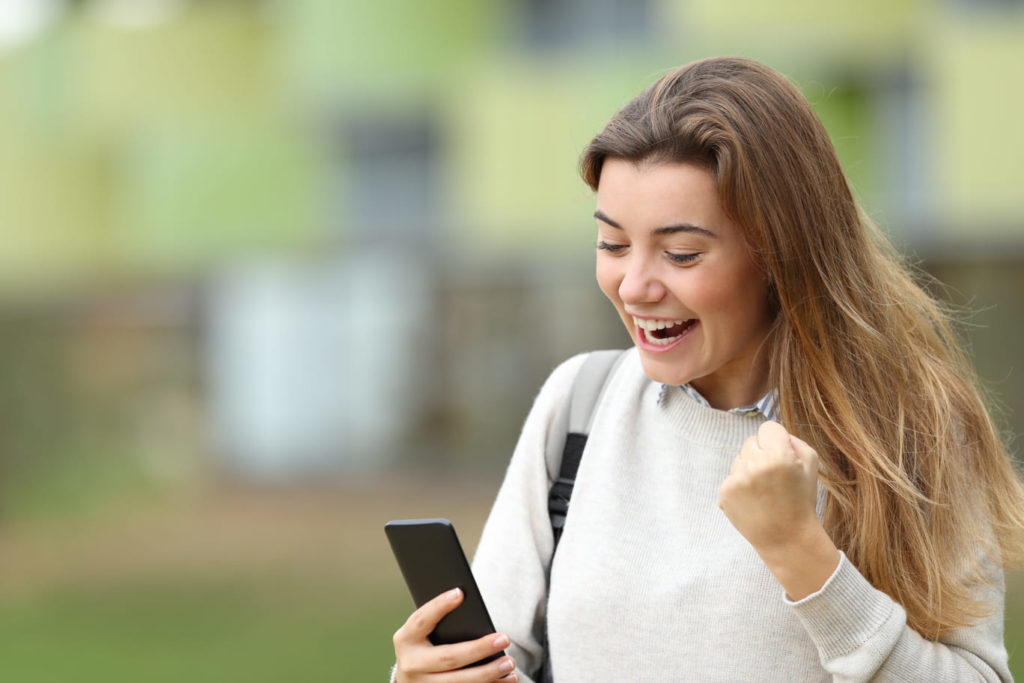 young woman excited while looking at her phone